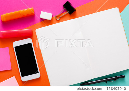 Creative minimal design, flat lay of workspace with stationery, smartphone, open blank notepad. Abstract colorful background with copy space on sketchbook, top view, mockup 138403940