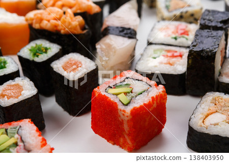 Japanese food restaurant delivery closeup - sushi and rolls platter set isolated at white background with wooden chopsticks taking one piece Japanese food restaurant delivery closeup - sushi and rolls platter set isolated at white background with wooden chopsticks taking one piece 138403950
