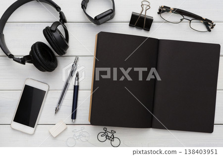Education, office and work concept, top view of black and white workplace. Stationery supplies - blank notepad, pens, binder clips, phone, watch on wooden desktop, flat lay, copy space, template Education, office and work concept, top view of black and white workplace. Stationery supplies - blank notepad, pens, binder clips, phone, watch on wooden desktop, flat lay, copy space, template 138403951