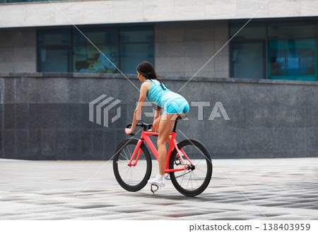 Sexy girl with bicycle. Young slim sexy sportive woman in blue shorts and white snickers long-haired, sensual posing with pink fix bicycle in urban city enviroment. Soft toned. Shaped buttocks. Sexy girl with bicycle. Young slim sexy sportive woman in blue shorts and white snickers long-haired, sensual posing with pink fix bicycle in urban city enviroment. Soft toned. Shaped buttocks. 138403959