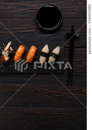 Colorful sushi platter in japanese restaurant, with chopsticks and soy sauce on dark wooden background, vertical, top view, flat lay Colorful sushi platter in japanese restaurant, with chopsticks and soy sauce on dark wooden background, vertical, top view, flat lay 138403960