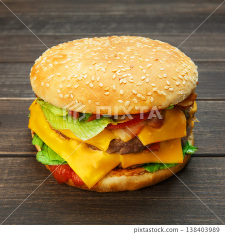 Classic american burger food. Big double cheese burger at wood. Hamburger with fresh vegetables and meat. Burger with cheese, beef, tomato, lettuce. Cheeseburger at rustic wooden background. Classic american burger food. Big double cheese burger at wood. Hamburger with fresh vegetables and meat. Burger with cheese, beef, tomato, lettuce. Cheeseburger at rustic wooden background. 138403989