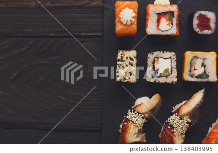 Sushi plate. Japanese food restaurant, unagi and salmon rolls on dark background. Top view with copy space on black wood Sushi plate. Japanese food restaurant, unagi and salmon rolls on dark background. Top view with copy space on black wood 138403995
