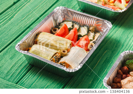 Healthy restaurant food delivery. Take away foil lunch boxes with copy space at green wood. Stuffed leek with fresh vegetables Healthy restaurant food delivery. Take away foil lunch boxes with copy space at green wood. Stuffed leek with fresh vegetables 138404136