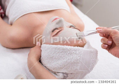 Face peeling mask, spa beauty treatment, skincare. Woman getting facial care by beautician at spa salon, side view, close-up Face peeling mask, spa beauty treatment, skincare. Woman getting facial care by beautician at spa salon, side view, close-up 138404161