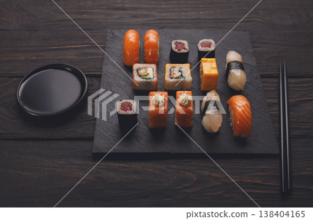 Colorful sushi and rolls platter in japanese restaurant, with chopsticks and soy sauce on dark background Colorful sushi and rolls platter in japanese restaurant, with chopsticks and soy sauce on dark background 138404165