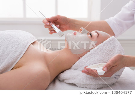 Face peeling mask, spa beauty treatment, skincare. Woman getting facial care by beautician at spa salon, side view, close-up 138404177
