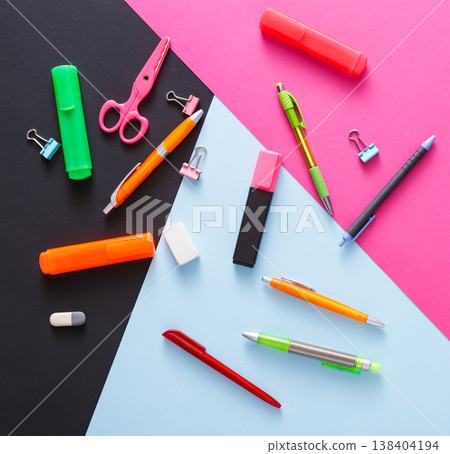 Stationery supplies and devices on pop art background. Top view, flat lay, mockup of creative work space at modern office with markers, rubbers, pens, scissors and binder clips Stationery supplies and devices on pop art background. Top view, flat lay, mockup of creative work space at modern office with markers, rubbers, pens, scissors and binder clips 138404194
