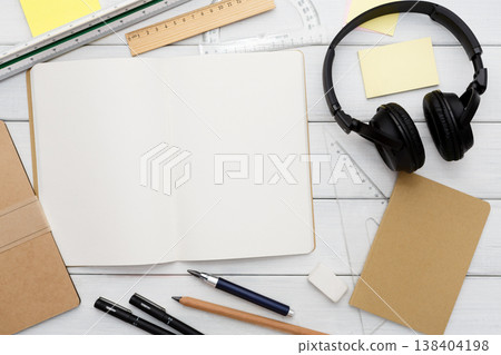 Workspace top view, education concept, modern workplace. Stationery supplies - blank notepad and headphones on white wooden desktop, flat lay, copy space, mockup Workspace top view, education concept, modern workplace. Stationery supplies - blank notepad and headphones on white wooden desktop, flat lay, copy space, mockup 138404198