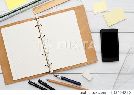 Workspace top view, education concept, modern workplace. Stationery supplies - blank notepad and mobile on white wooden desktop, flat lay, copy space, mockup 138404230