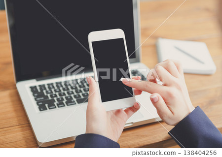 Female using computer and mobile phone, selective focus, close-up, copy space on the screen Female using computer and mobile phone, selective focus, close-up, copy space on the screen 138404256