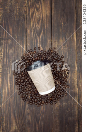 Mockup coffee in a disposable cup on a wooden table and a coffee grains, dark background. Top view 138404336