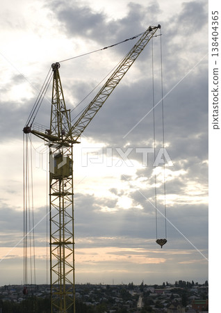 Industrial construction cranes and building silhouettes over sun at sunrise Industrial construction cranes and building silhouettes over sun at sunrise 138404365