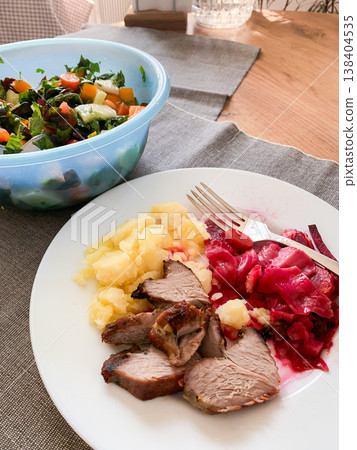 A plate of healthy breakfast includes mashed potatoes, turkey meat, and fermented cabbage along with a bowl of fresh salad on a wooden table. This meal is served in a simple dining area A plate of healthy breakfast includes mashed potatoes, turkey meat, and fermented cabbage along with a bowl of fresh salad on a wooden table. This meal is served in a simple dining area 138404535