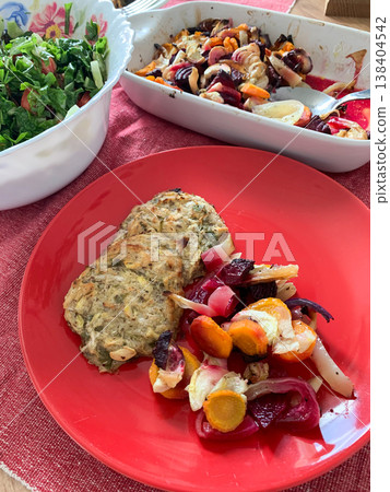 A plate holds zucchini pancakes alongside baked vegetables and a fresh green salad. This healthy breakfast offers gluten-free options for anyone looking for nutritious meals A plate holds zucchini pancakes alongside baked vegetables and a fresh green salad. This healthy breakfast offers gluten-free options for anyone looking for nutritious meals 138404542
