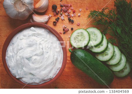 Greek zajiki sauce, in a clay bowl, on a wooden board, with ingredients, top view, no people, Greek zajiki sauce, in a clay bowl, on a wooden board, with ingredients, top view, no people, 138404569