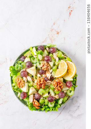 Fresh Waldorf salad, celery stalk with chicken, apple and walnuts, grapes, herbs, homemade, without people, 138404656