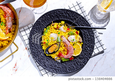 Dinner table with seafood paella and drink in a cozy setting during the evening hours Dinner table with seafood paella and drink in a cozy setting during the evening hours 138404666
