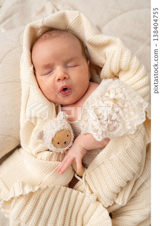 Cute newborn baby yawning during sleep, wrapped in soft knitted fabric. Natural newborn photography capturing tenderness, calmness and early childhood moments. Cute newborn baby yawning during sleep, wrapped in soft knitted fabric. Natural newborn photography capturing tenderness, calmness and early childhood moments. 138404755