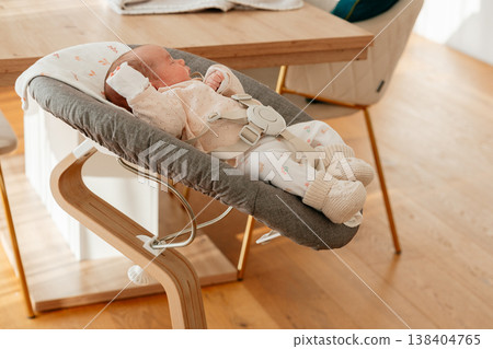 Infant lying comfortably in ergonomic baby rocker. Minimal home setting suitable for baby products marketing, parenting blogs and family lifestyle concepts. Infant lying comfortably in ergonomic baby rocker. Minimal home setting suitable for baby products marketing, parenting blogs and family lifestyle concepts. 138404765