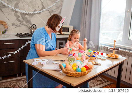 A cheerful Caucasian family lifestyle moment as a mother and daughter paint festive paper masks. 138407435