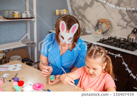 A cozy Caucasian family prepares for Easter by decorating paper masks together indoors. A cozy Caucasian family prepares for Easter by decorating paper masks together indoors. 138407439