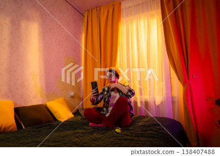 Young female teenager relaxing online in sunset glow. Concept of technology at home. Low angle view 138407488