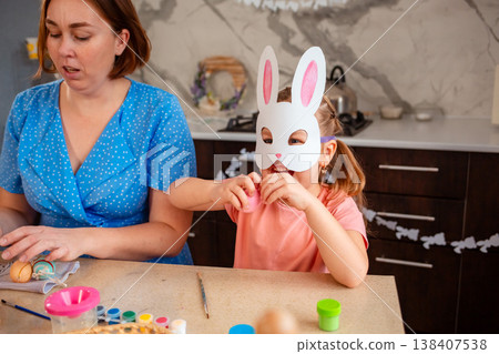 Caucasian mother and daughter preparing for Easter by coloring eggs, building memories and spending meaningful time. Concept of family traditions, childhood and festive preparation. Mid shot Caucasian mother and daughter preparing for Easter by coloring eggs, building memories and spending meaningful time. Concept of family traditions, childhood and festive preparation. Mid shot 138407538
