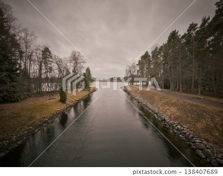 Tranquil Riverside Setting Featuring Leafless Pines And Overcast Sky 138407689
