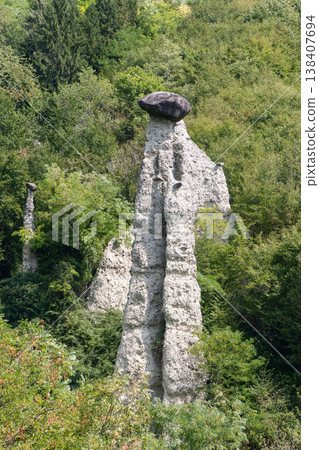 Towering capped earth pyramid  Zone Rock Pyramids shows pale erosion column with dark boulder 138407694