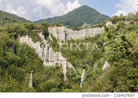 White hoodoos and pale erosion cliffs at Zone Rock Pyramids spread beneath a conical mountain 138407697