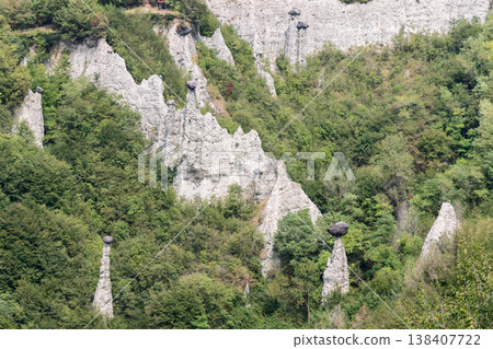 Capped earth pyramids in Zone Rock reserve near Lake Iseo rise pale mineral towers through woodland 138407722