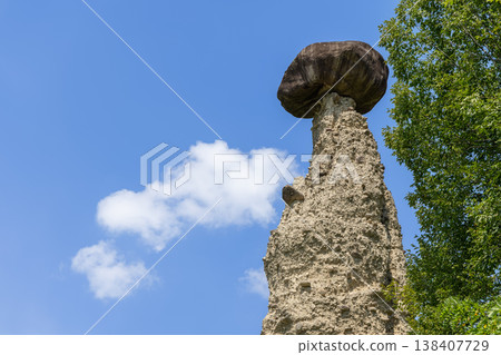 Low angle close view of a capped hoodoo at the Pyramids Zone with pale tower dark boulder in summer Low angle close view of a capped hoodoo at the Pyramids Zone with pale tower dark boulder in summer 138407729