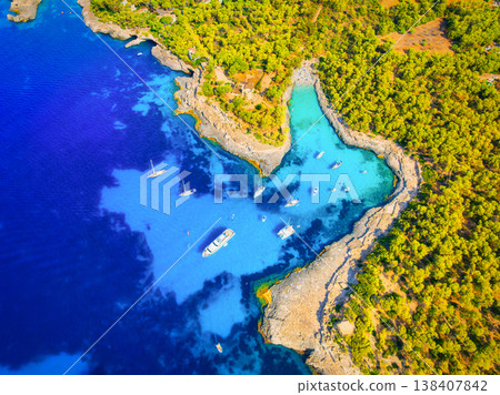 Top down aerial drone view of luxury yachts and boats in a turquoise bay with crystal clear water. 138407842