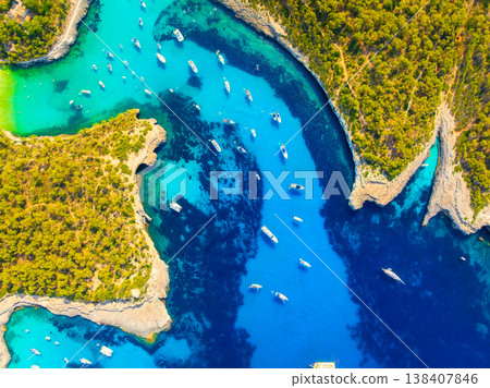 Top down aerial drone view of luxury yachts and boats in a turquoise bay with crystal clear water. Top down aerial drone view of luxury yachts and boats in a turquoise bay with crystal clear water. 138407846