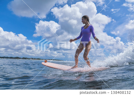 Cheerful Young Lady Balances On surfboard Amid Stormy Skies And Powerful Seas Cheerful Young Lady Balances On surfboard Amid Stormy Skies And Powerful Seas 138408132