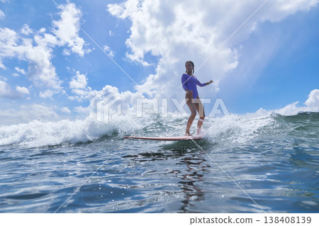 Youthful Girl Skillfully Maintains Her Balance On surfboard Amidst Ocean Scenery Youthful Girl Skillfully Maintains Her Balance On surfboard Amidst Ocean Scenery 138408139