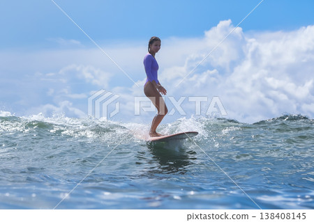 Teenage Girl Surfing Glossy Blue Crest With Bold Stances And Bright Sky Teenage Girl Surfing Glossy Blue Crest With Bold Stances And Bright Sky 138408145