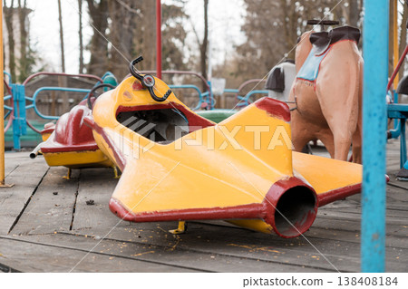 Abandoned Vintage Yellow and Red Airplane Ride at Defunct Amusement Park With Weathered Wooden Decking and Background Trees Abandoned Vintage Yellow and Red Airplane Ride at Defunct Amusement Park With Weathered Wooden Decking and Background Trees 138408184