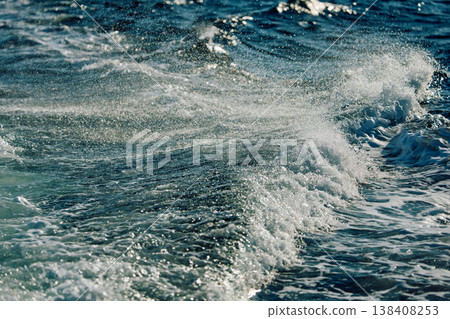 A wave of the Barents Sea breaks against a strong wind in sunny weather 138408253