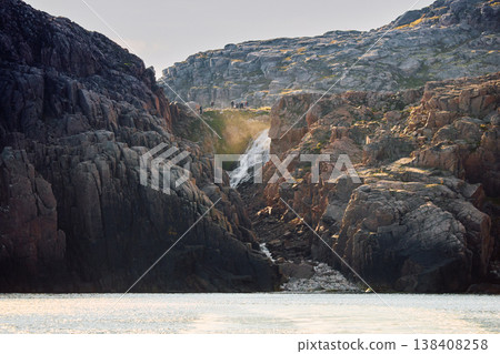 Russia, Teriberka, many people admire the waterfall at the edge of the Battery waterfall at sunet, Arctic landscape with a view of a flowing waterfall in the northern fjord 138408258