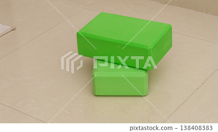 Yoga equipment flat lay isolated, tiled floor background. Pilates and fitness blocks, belt and wheel . High quality photo 138408383