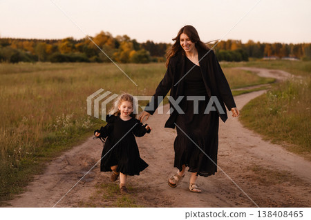 Mother And Daughter Enjoying Sunset. Parent And Child Strolling Along Countryside Path Mother And Daughter Enjoying Sunset. Parent And Child Strolling Along Countryside Path 138408465