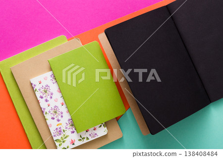 Stylish mockup with set of various colorful notebooks and black open sketchbook on creative multicolored work space background, copy space, flat lay, concept of start-up and stationery supplies Stylish mockup with set of various colorful notebooks and black open sketchbook on creative multicolored work space background, copy space, flat lay, concept of start-up and stationery supplies 138408484