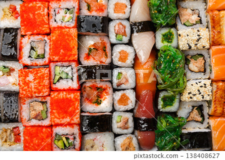 Sushi and rolls pattern background, japanese restaurant delivery top view. Salmon, unagi, california and other healthy meals Sushi and rolls pattern background, japanese restaurant delivery top view. Salmon, unagi, california and other healthy meals 138408627