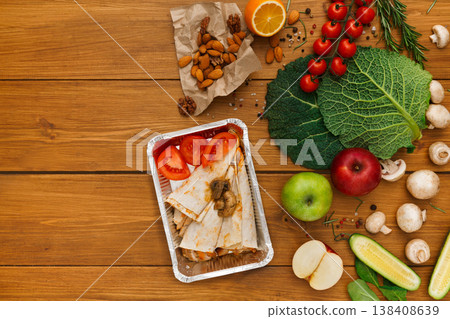 Healthy food delivery background. Lunch box with pancakes, chicken and tomatoes on rustic wood table, copy space Healthy food delivery background. Lunch box with pancakes, chicken and tomatoes on rustic wood table, copy space 138408639