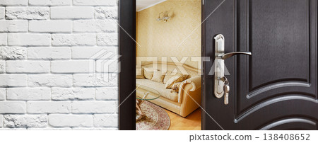 Half opened door to a living room. Door handle, door lock. Lounge door half open. Opening door. Privacy, safety concept. Entrance to the room. Door at white brick wall, modern interior design. Half opened door to a living room. Door handle, door lock. Lounge door half open. Opening door. Privacy, safety concept. Entrance to the room. Door at white brick wall, modern interior design. 138408652