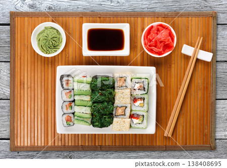 Japanese food restaurant delivery - sushi maki, unagi and roll platter set on mat on gray wood background, above view Japanese food restaurant delivery - sushi maki, unagi and roll platter set on mat on gray wood background, above view 138408695