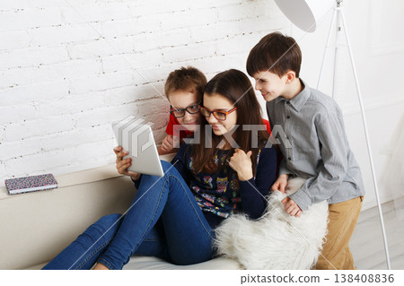 Group of kids in eye glasses look into tablet. Children computer games, social networks and media addiction concept. Girl and boys with tablet. Communication problems Group of kids in eye glasses look into tablet. Children computer games, social networks and media addiction concept. Girl and boys with tablet. Communication problems 138408836