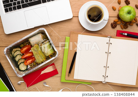 Healthy food delivery. Lunch box with diet meal on workplace, flat lay of wooden desktop with foiled container Healthy food delivery. Lunch box with diet meal on workplace, flat lay of wooden desktop with foiled container 138408844